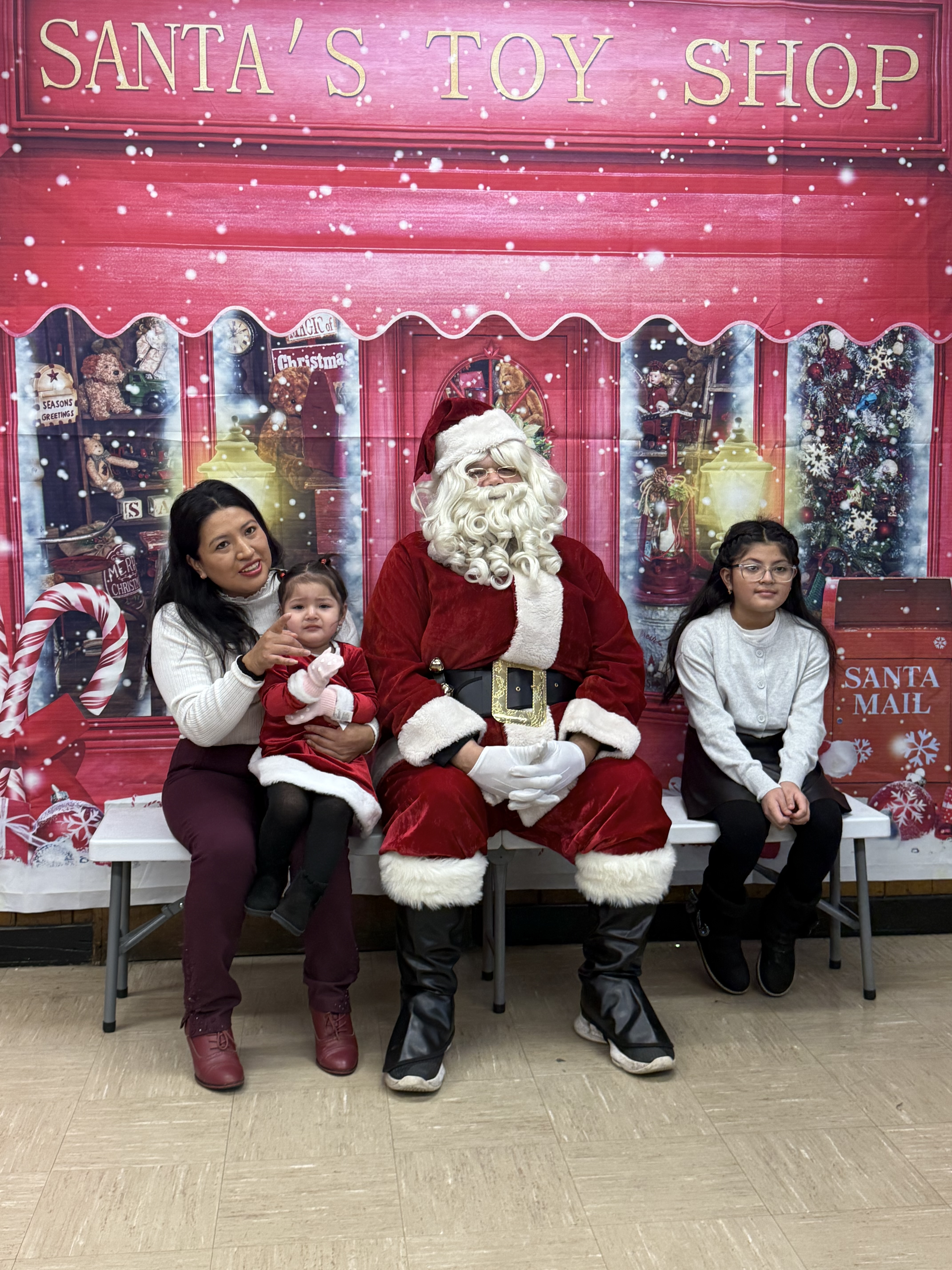 Photograph of family with Santa in front of toy shop backdrop.